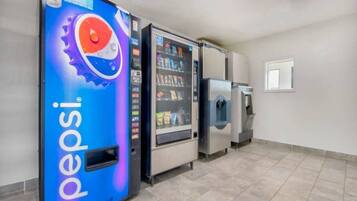 Et område med salgsautomater, inklusive en Pepsi-reklame, en snackautomat og en vanddåse-dispenser.