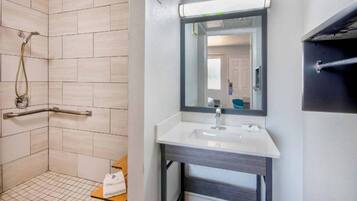 Ein Badezimmer mit Dusche, Waschbecken und Spiegel.