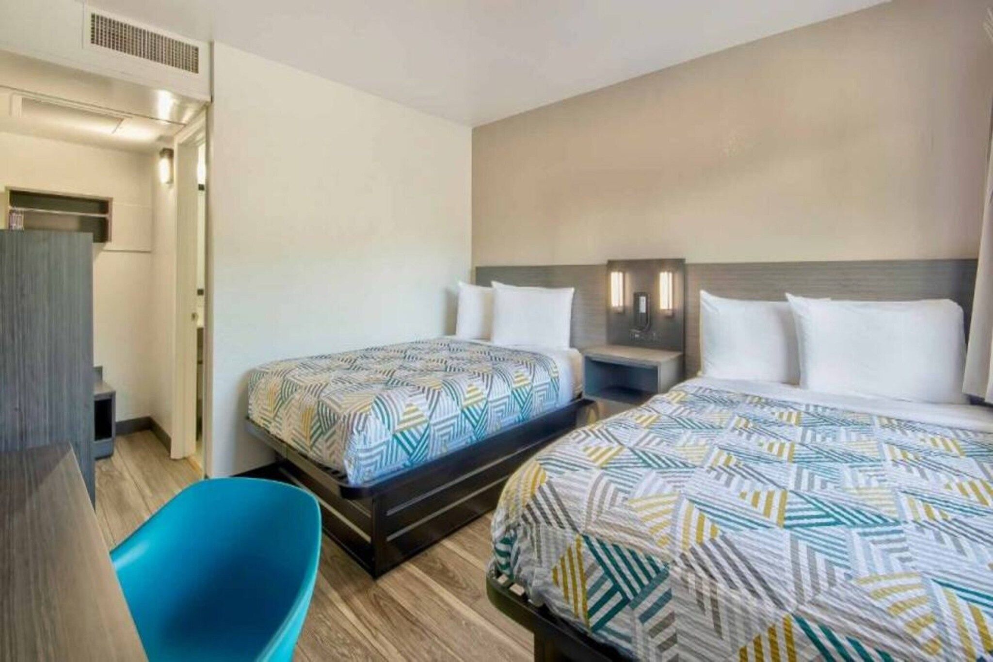 Una habitación de hotel con dos camas, un escritorio y una silla.