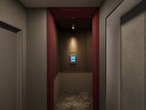 A narrow hallway with a wooden wall and a red accent wall. A digital elevator control panel is visible at the end of the hallway. - illi Vau Hamamatsucho (Minato-ku)