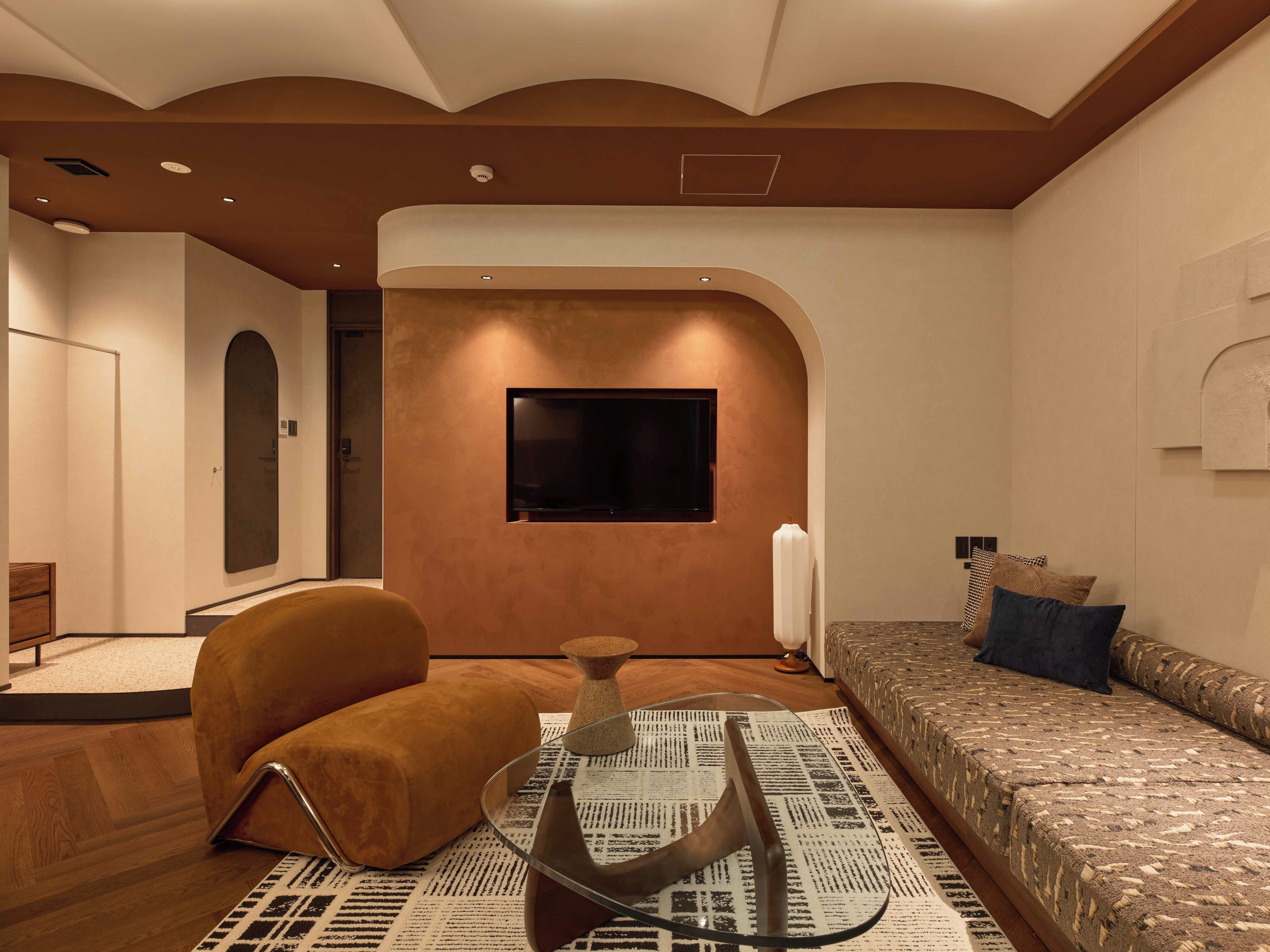 A modern living room with a sofa, a television mounted on the wall, and a patterned rug.