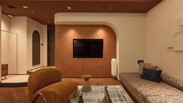 A modern living room with a sofa, a television mounted on the wall, and a patterned rug.