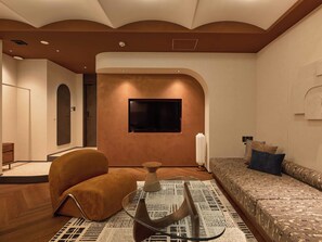 A modern living room with a sofa, a television mounted on the wall, and a patterned rug. - illi Vau Hamamatsucho (Minato-ku)