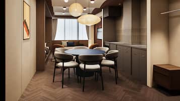 A modern dining area with a round table and chairs, a kitchen with wooden cabinets, and pendant lighting.