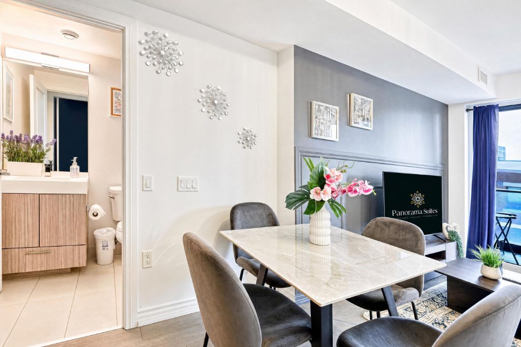 A modern dining area with a marble table, black chairs, and a vase with flowers.