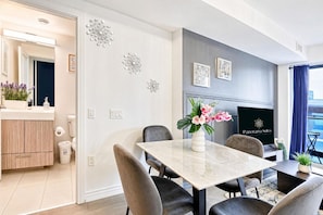 A modern dining area with a marble table, black chairs, and a vase with flowers. - StayToronto -  Urban Serenity 1BR Suite - Downtown (Toronto)