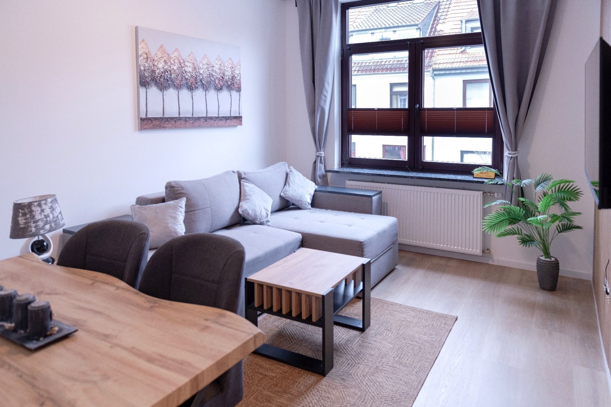 A modern living room with a sofa, coffee table, and a dining table.
