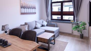 A modern living room with a sofa, coffee table, and a dining table.