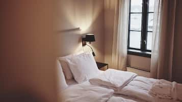 Ein Hotelzimmer mit einem Bett, einem Nachttisch, einer Lampe und einem Fenster mit Vorhängen.