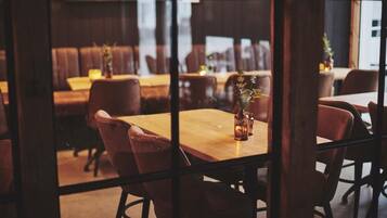 A restaurant interior with wooden tables and chairs, a glass partition, and a view of the street outside.