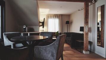 A modern living room with a round table and chairs, a sofa, and a television.