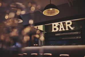 Un espace bar avec une enseigne indiquant « BAR » et une rangée de verres disposés sur des étagères.
