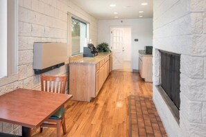 Une cuisine avec une table en bois, un comptoir et une cheminée.