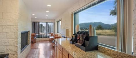 A modern kitchen with a granite countertop, wooden cabinets, and a large window offering a view of the outdoors.