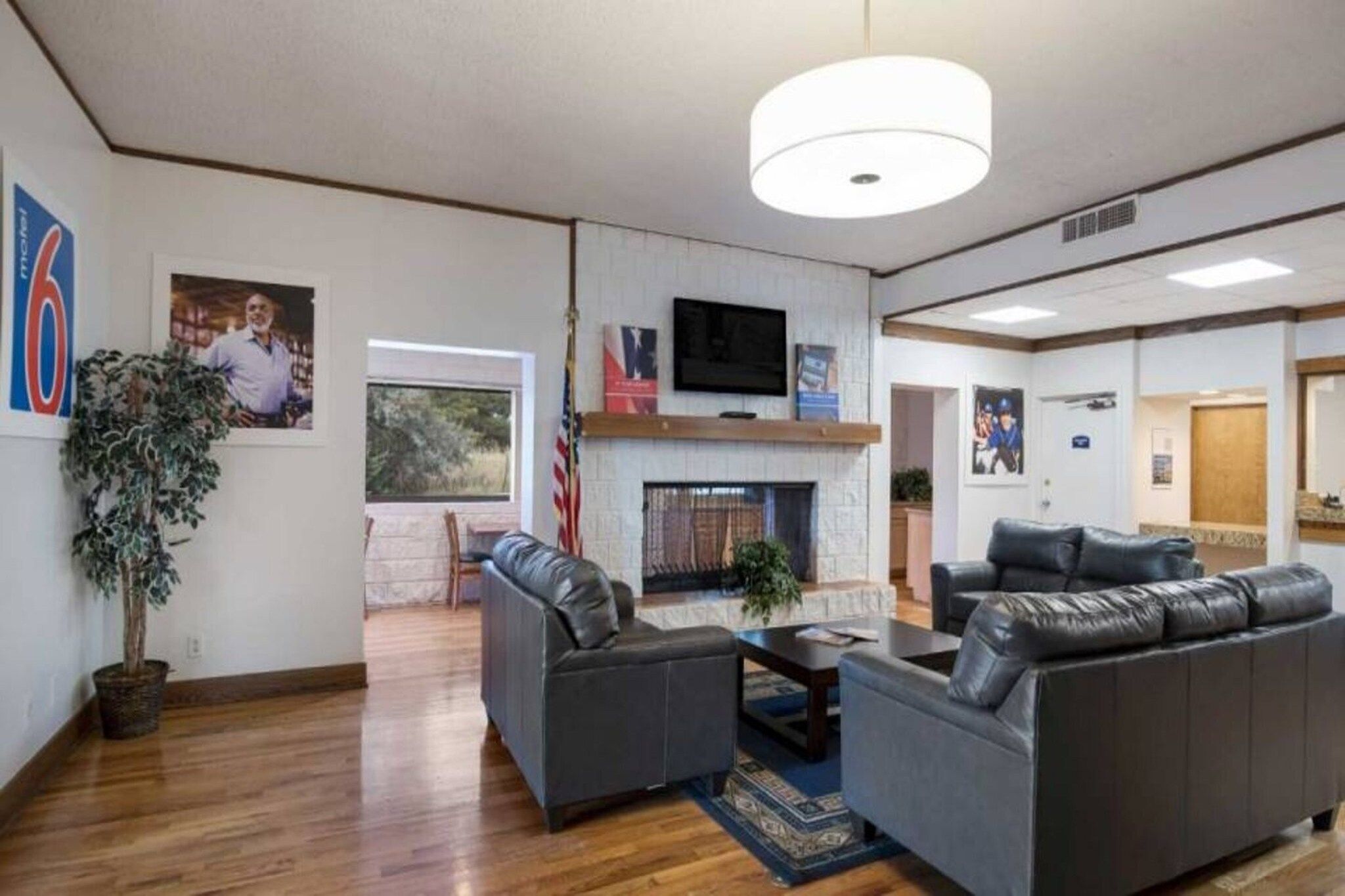 A spacious living room with a fireplace, leather sofas, a flat-screen TV, and a large window.