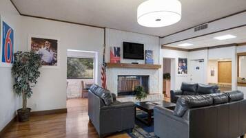 A spacious living room with a fireplace, leather sofas, a flat-screen TV, and a large window.