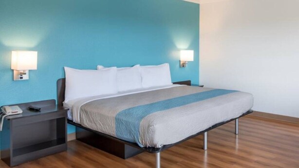 Una habitación de hotel con cama, mesitas de noche y lámparas de pared.
