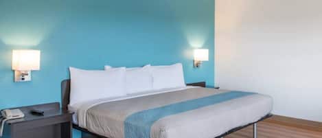 Une chambre d’hôtel avec un lit, des tables de chevet et des lampes fixées au mur.