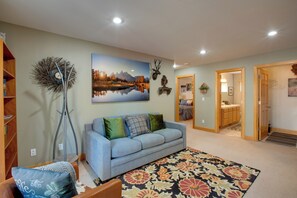 A living room with a sofa, a decorative floor lamp, a painting, and a hallway leading to another room. - Walk to Lake! Spacious Tahoe Retreat w/ Yard (South Lake Tahoe)