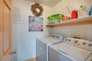 A laundry room with two white Whirlpool washers, a green basket, a red bottle, and a wall-mounted shelf with various items. - Walk to Lake! Spacious Tahoe Retreat w/ Yard (South Lake Tahoe)