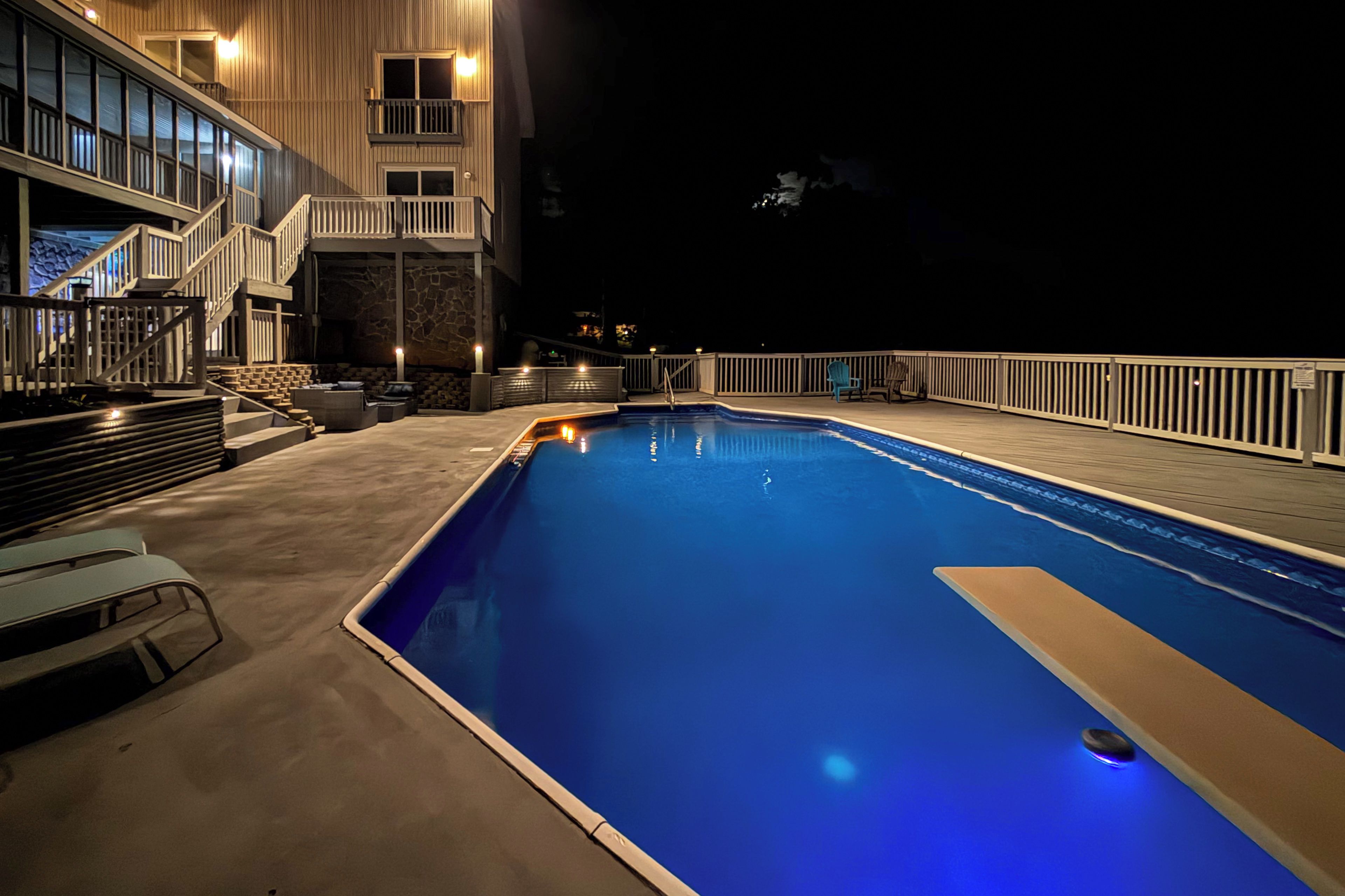 A swimming pool with a wooden deck and a stone wall.