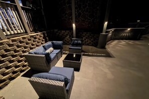 Un espace extérieur aménagé avec des meubles en osier et un mur en pierre en arrière-plan.