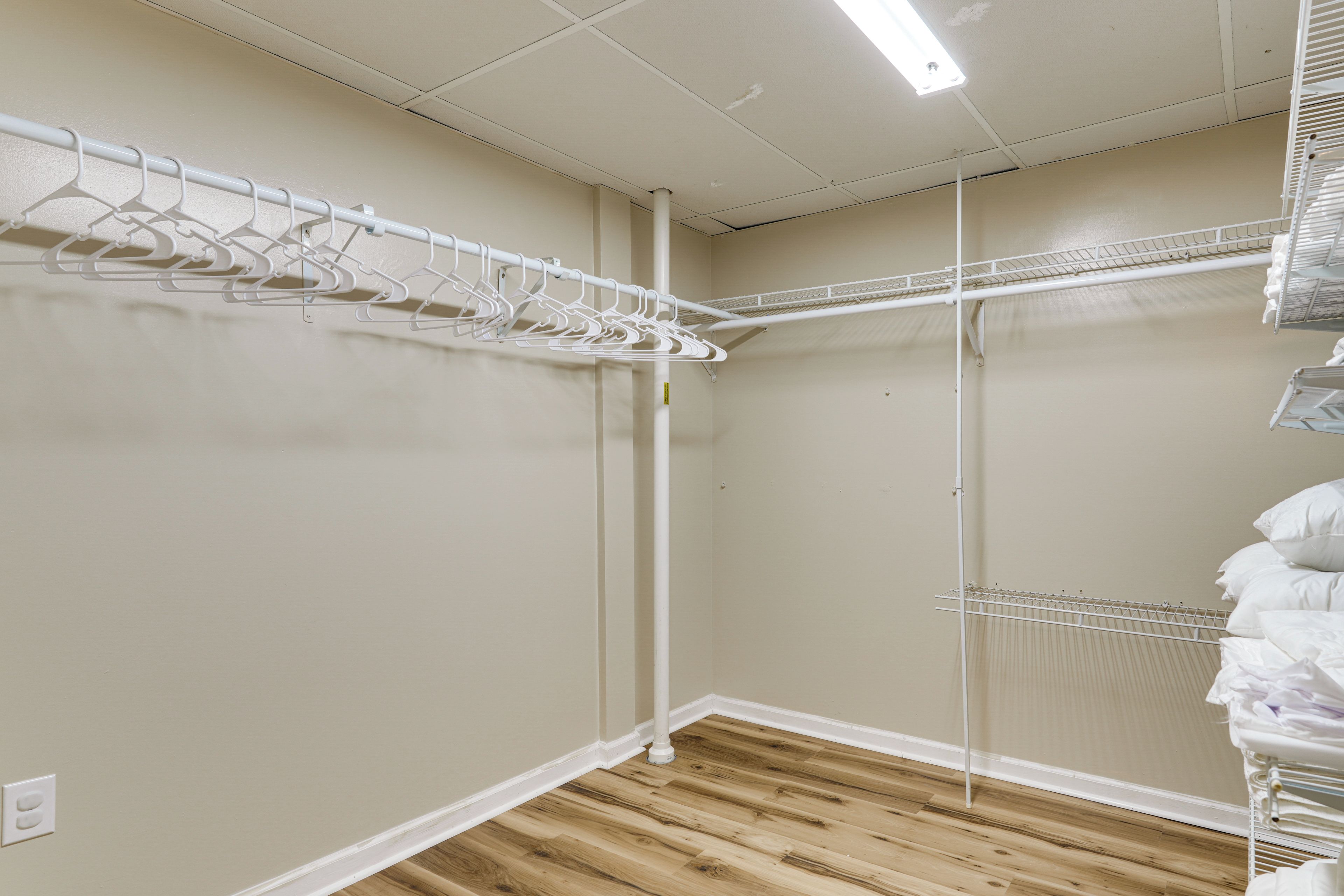 Un vestidor con suelo de madera, paredes blancas e iluminación fluorescente en el techo.