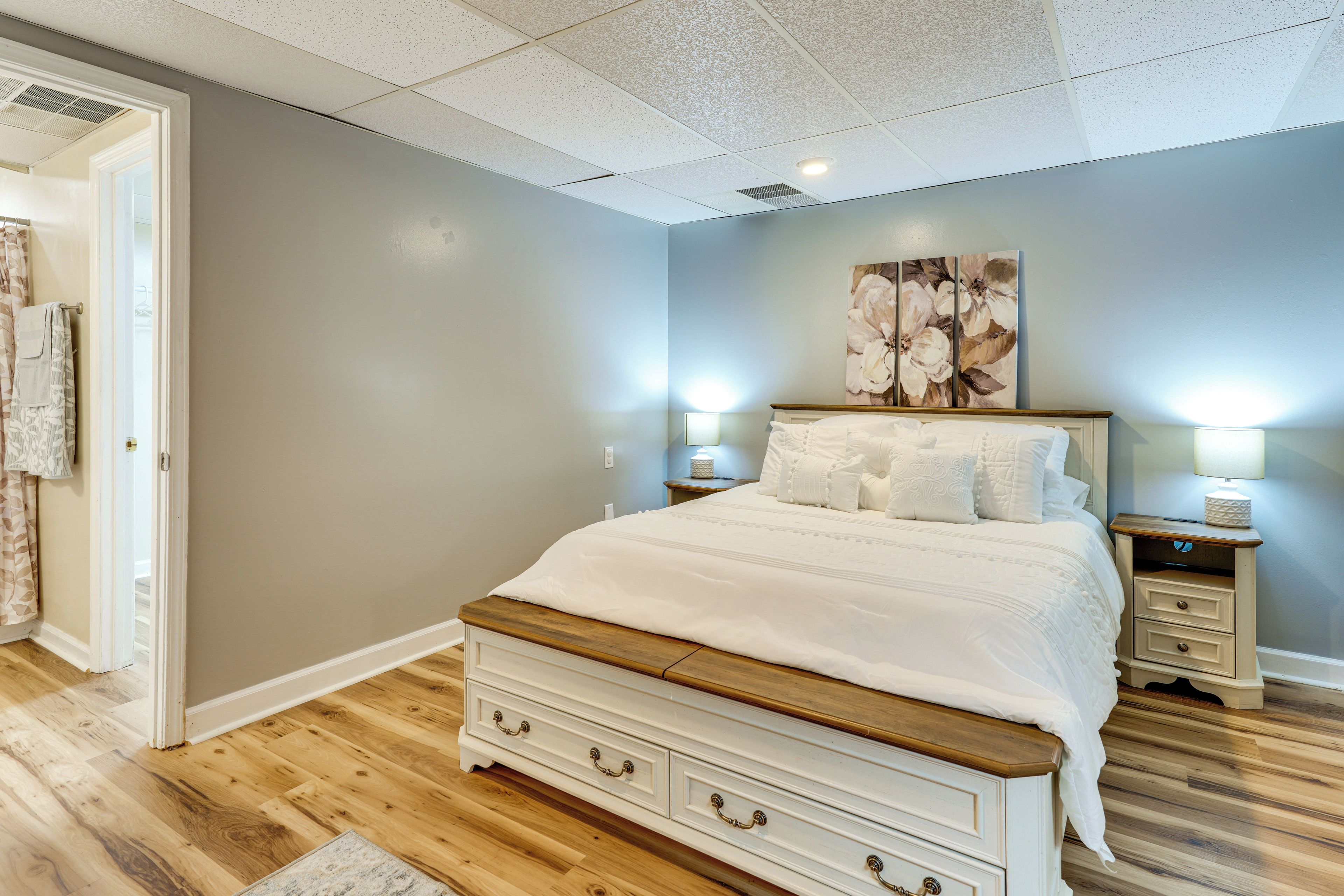 A bedroom with a bed, nightstands, a dresser, and a door leading to a bathroom.