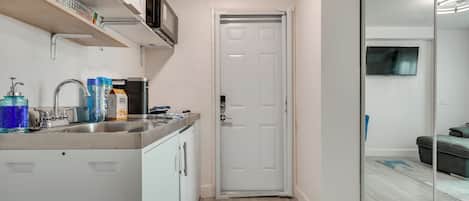 A compact kitchen with a built-in microwave, a sink with a faucet, and a small refrigerator.