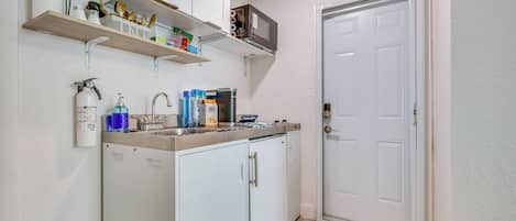 Cocina pequeña con armarios blancos, microondas y fregadero.