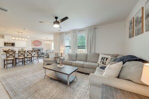 A modern living room with a sofa, coffee table, and a dining area with chairs and a table. - Walk to Tiger Stadium! New Modern Home w/ Yard (Baton Rouge)