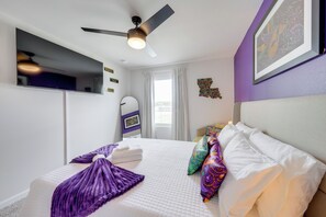A hotel room with a bed, a ceiling fan, a window with curtains, and a wall with a framed picture. - Walk to Tiger Stadium! New Modern Home w/ Yard (Baton Rouge)