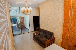 A modern interior with a sofa, a chandelier, and a view of a staircase leading to another room.