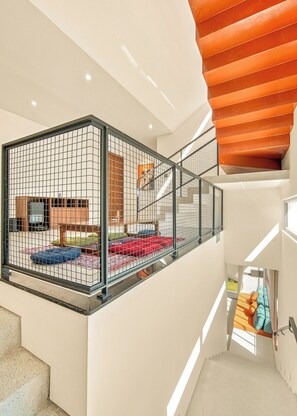 A multi-level interior with a glass-enclosed balcony area, a staircase, and a view of the outdoors. - The RED Signature 5br sunset (Đà Nẵng)