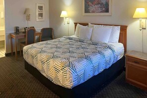 Une chambre d’hôtel comprenant un lit, des tables de chevet, un bureau, des chaises et des lampes fixées au mur.