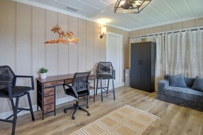 A room with a wooden desk, two chairs, a sofa, a decorative wall piece, and a wardrobe. - 8 Mi to New Smyrna Beach! Home w/ Poolside Oasis (Edgewater)