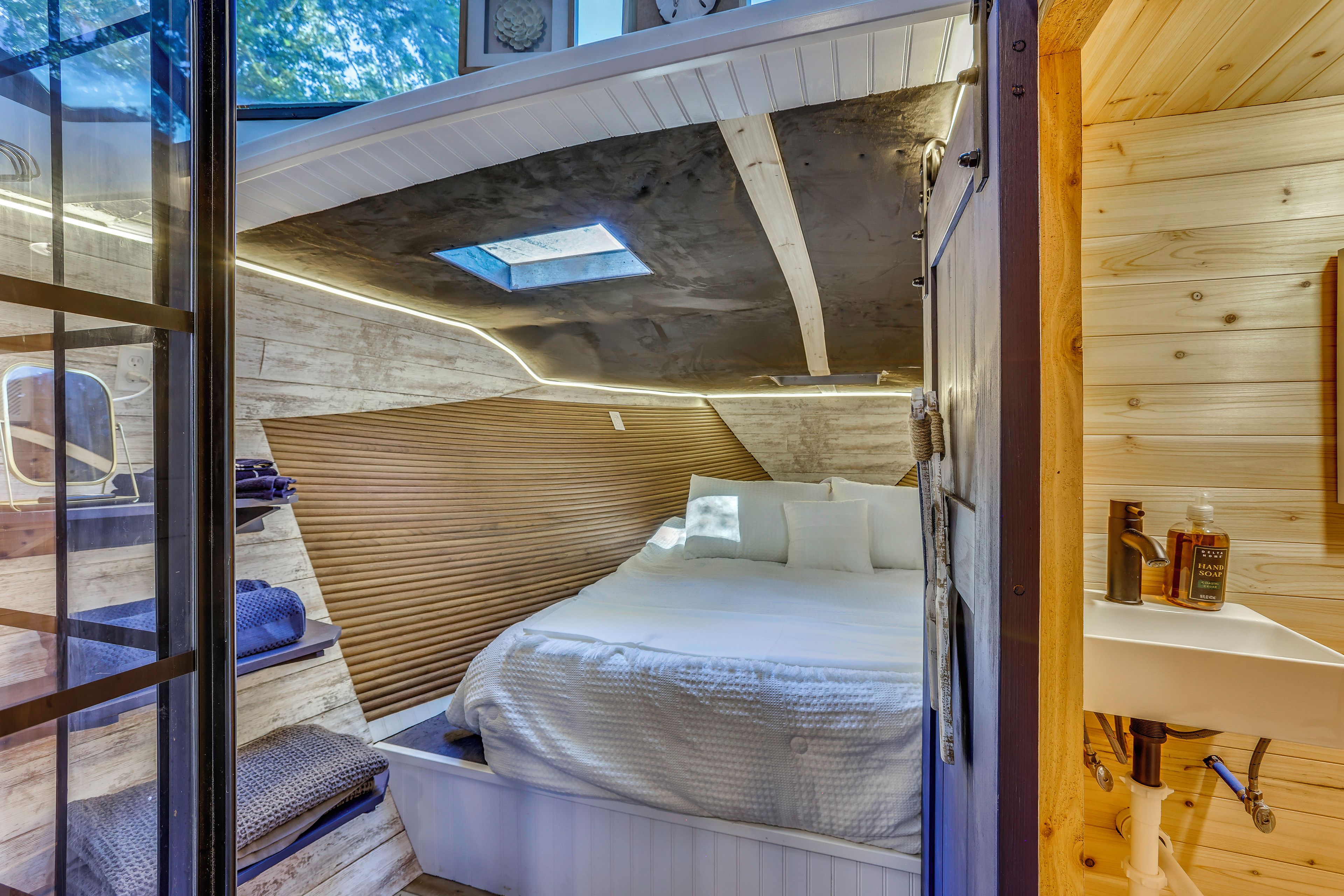 Een compacte, moderne kamer met een stapelbed, een klein zithoekje en een houten plafond.