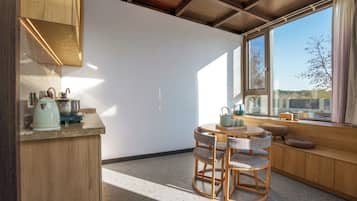 Cocina compacta con una mesa redonda y sillas, una ventana con vistas y un banco empotrado con cojines.