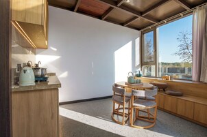 A compact kitchen with a round table and chairs, a window with a view, and a built-in bench with cushions.
