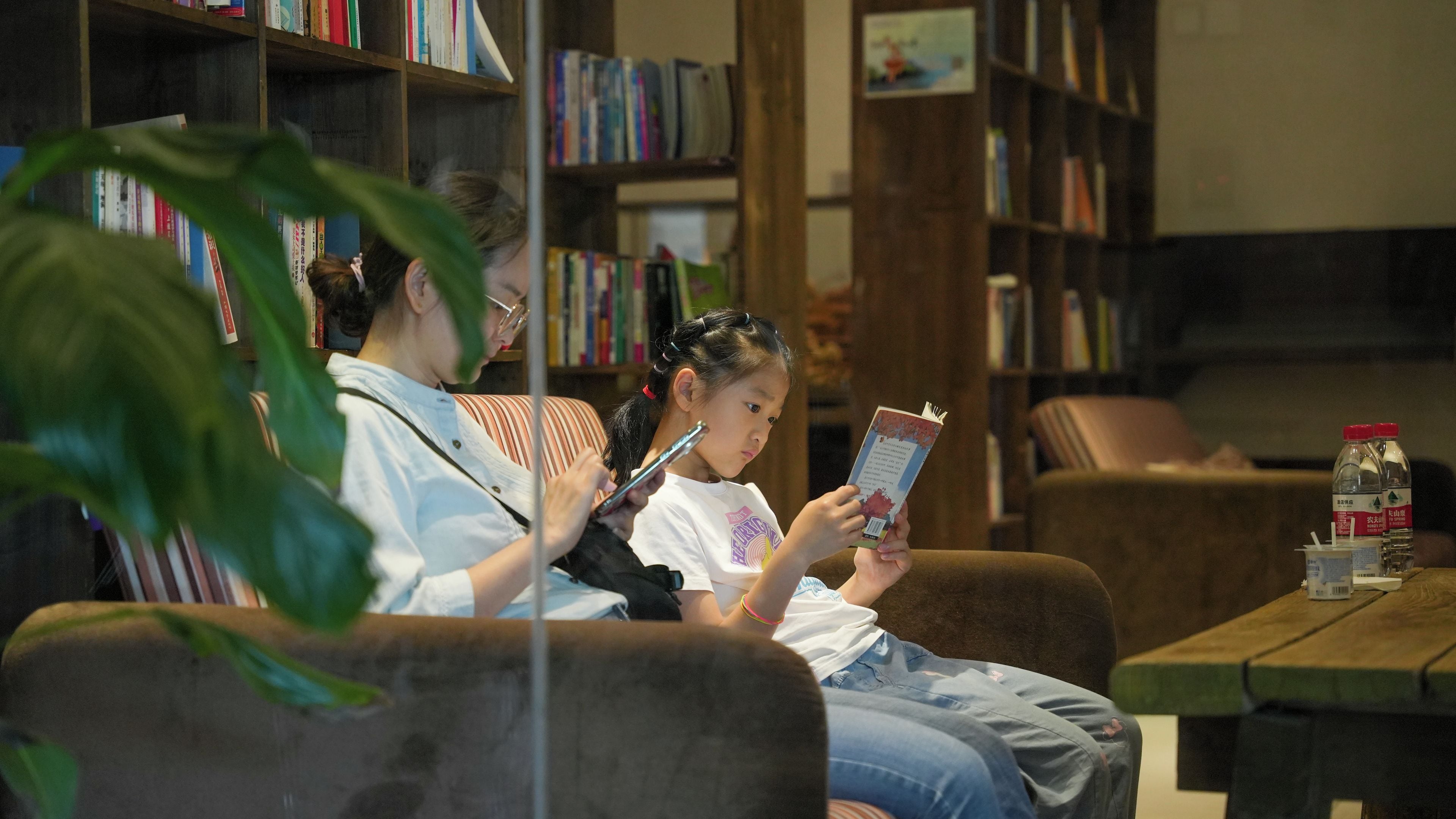 Un espacio tipo biblioteca con estanterías, un sofá y una mesa con una botella.