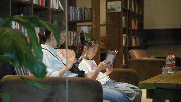 Un espacio tipo biblioteca con estanterías, un sofá y una mesa con una botella.