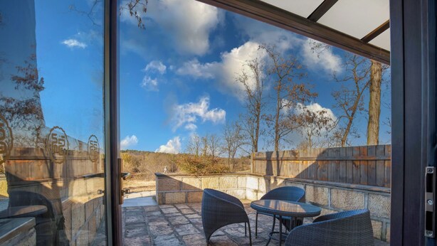 A patio with stone flooring, wicker furniture, and a view of a natural landscape through a glass door. - Donghai Forest Hot Spring Hotel (Lianyungang)