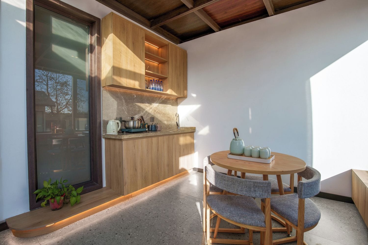 Una cocina moderna con armarios de madera, estufa integrada y una mesa de comedor redonda con sillas.