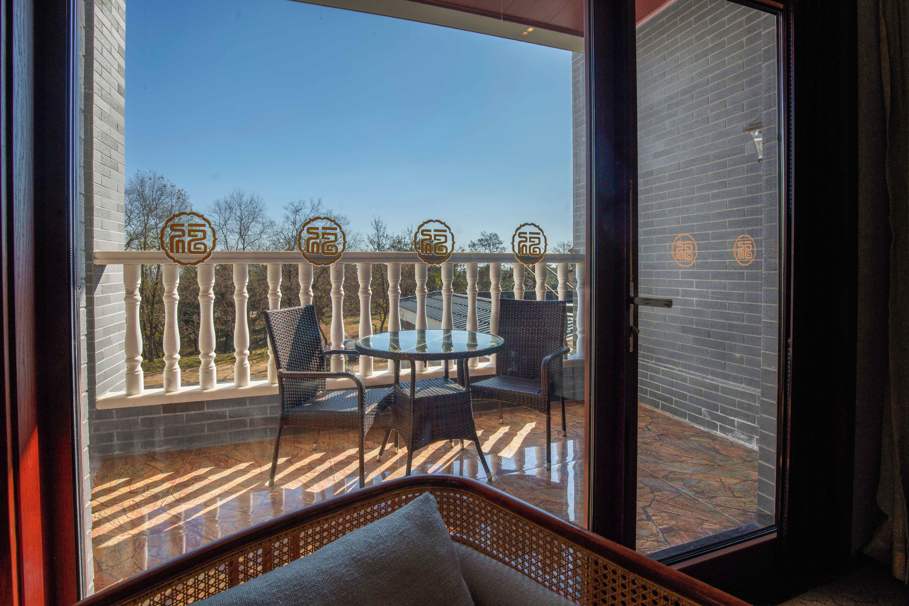A balcony with a glass door, wicker furniture, and a view of trees.