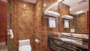 A modern bathroom with a marble wall, a toilet, a sink, and a glass shower enclosure. - Donghai Forest Hot Spring Hotel (Lianyungang)
