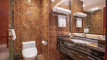 Une salle de bain moderne avec un mur en marbre, des toilettes, un lavabo et une douche à parois de verre.