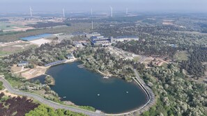 An aerial view of a campus with a lake, buildings, and wind turbines in the background. - Donghai Forest Hot Spring Hotel (Lianyungang)