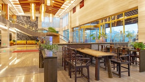 A modern hotel lobby with a marble floor, wooden furniture, and a staircase leading to upper levels. - Donghai Forest Hot Spring Hotel (Lianyungang)