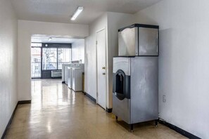 Un lavadero con una lavadora y secadora industriales de gran tamaño, una puerta que da a otra habitación y vistas al exterior a través de una ventana.