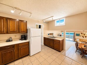 A kitchen with wooden cabinets, a white refrigerator, and a dining area with a table and chairs.